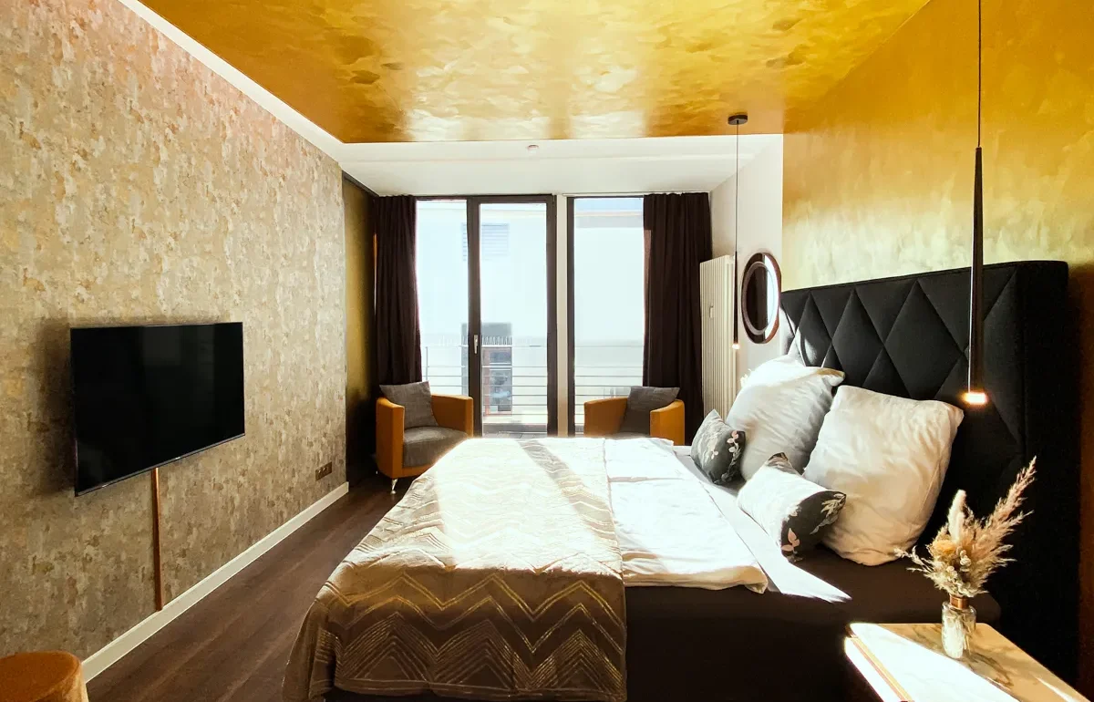 Sonnendurchflutetes Schlafzimmer des Sunrise Apartments mit Bett und Terrasse, spiegelt die liebevolle Detailgestaltung und die einzigartige Themenvielfalt unserer Ferienwohnungen in Leipzig wider.