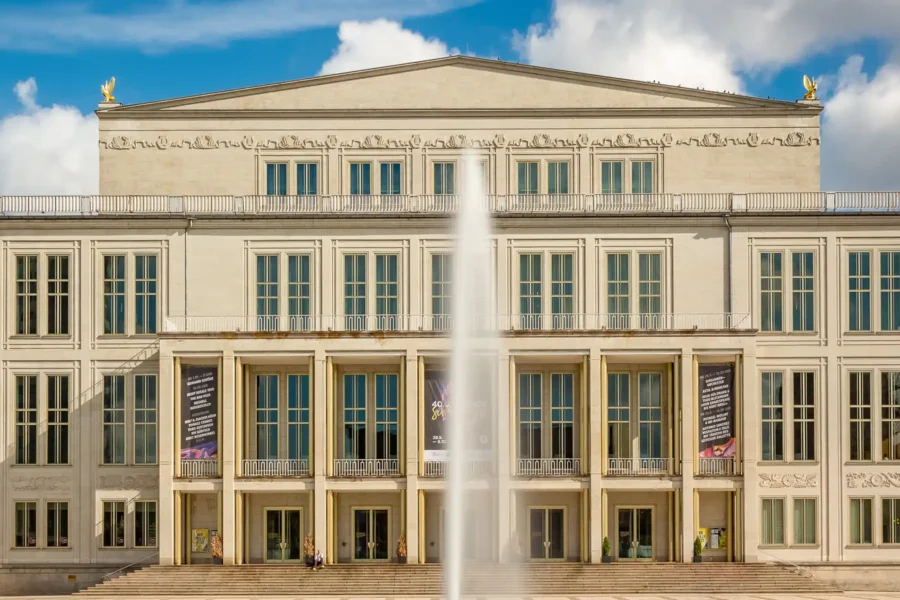 Ansicht der Oper Leipzig mit ihrer beeindruckenden Fassade und dem weitläufigen Vorplatz bei Sonnenschein.