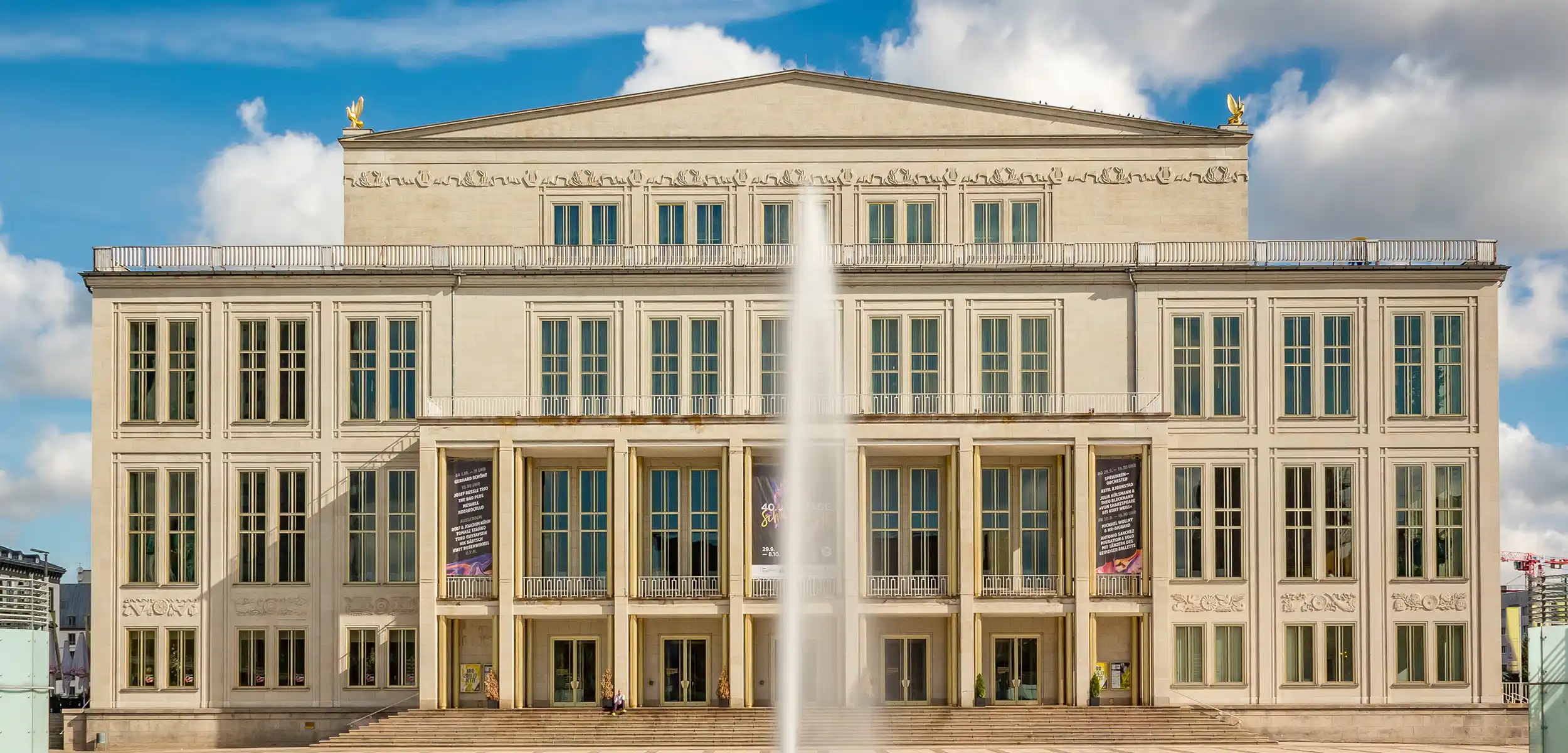Ansicht der Oper Leipzig mit ihrer beeindruckenden Fassade und dem weitläufigen Vorplatz bei Sonnenschein.