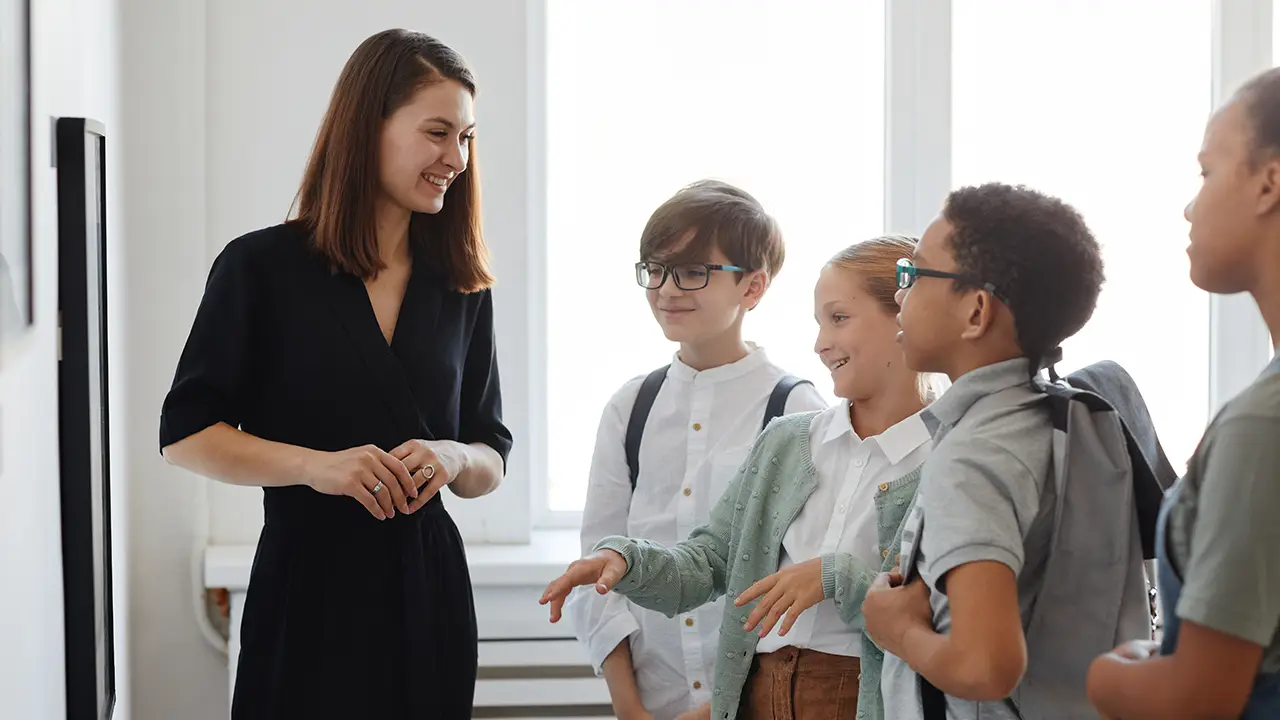 Eine Frau führt eine Gruppe von Schulkindern durch ein Museum und erklärt ihnen ein Kunstwerk.