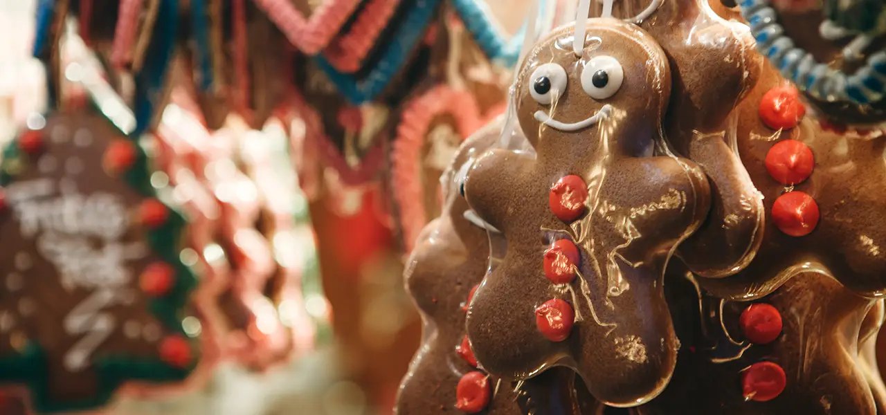 Lebkuchenmännchen mit Zuckerdekoration, verpackt in transparenter Folie, hängt an einem Weihnachtsmarktstand.