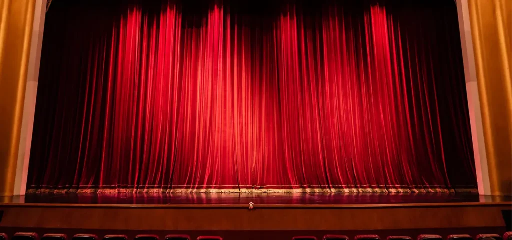 Geschlossene rote Samtvorhänge auf einer Theaterbühne der Musikalischen Komödie, umrahmt von goldenen Details.