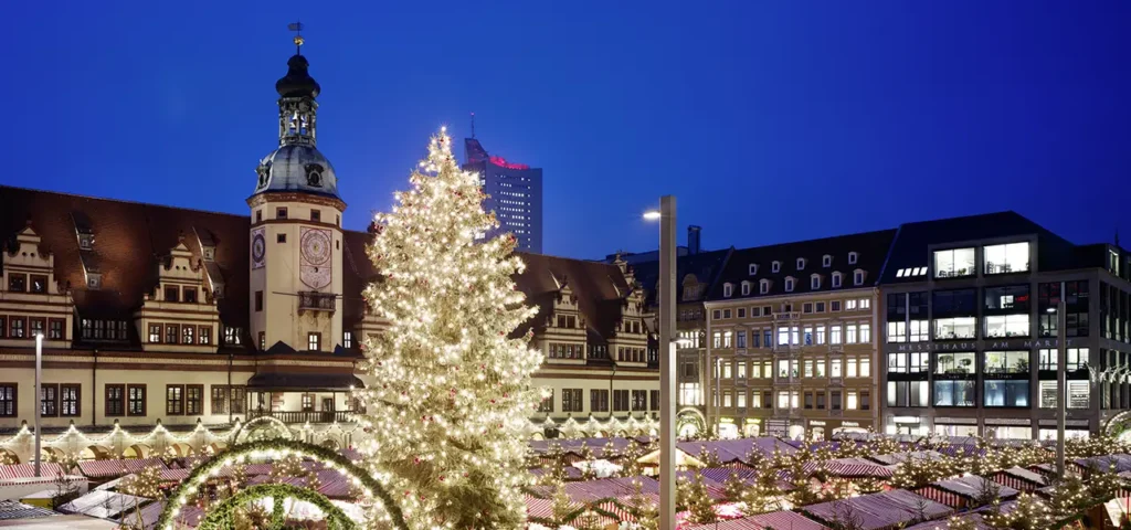 Leipziger Weihnachtsmarkt auf dem Marktplatz bei Nacht mit beleuchtetem Weihnachtsbaum und historischer Kulisse des Alten Rathauses.